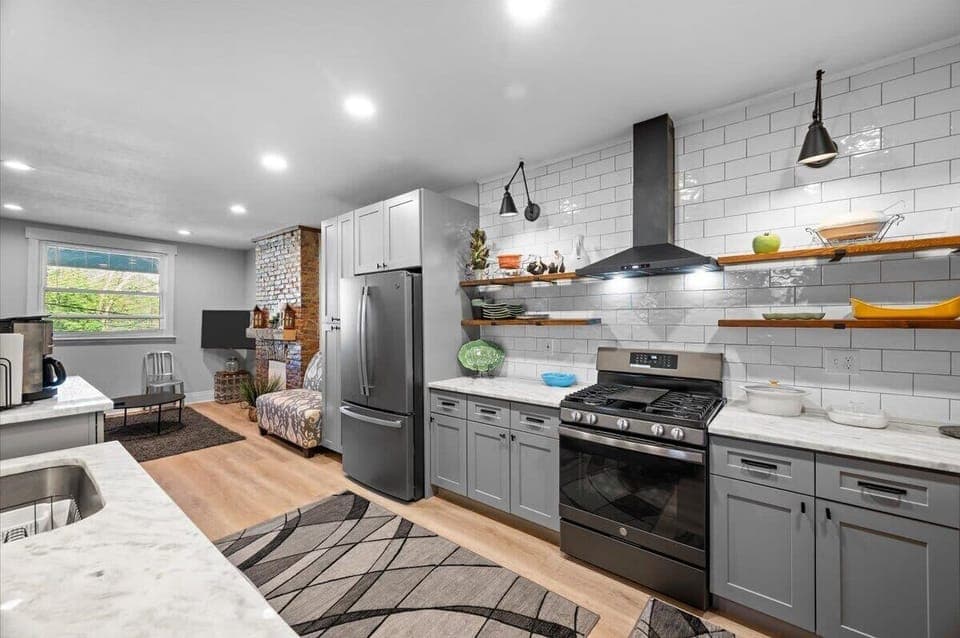 A  shot of the large kitchen, which features quartz countertops, full tile blacksplash, gas range with 5 burner cook top, as well as a french door fridge with ice/water. This area flows directly into the living and dining rooms.