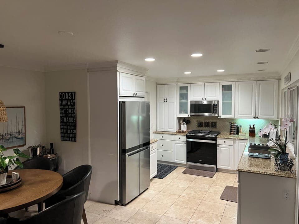 Kitchen area with refrigerator, gas stove/range and door leading to the garage.
