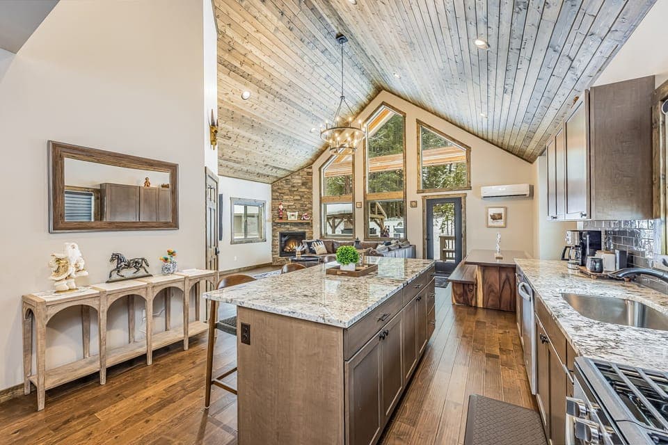 Chic granite island anchors this open-concept kitchen to living room