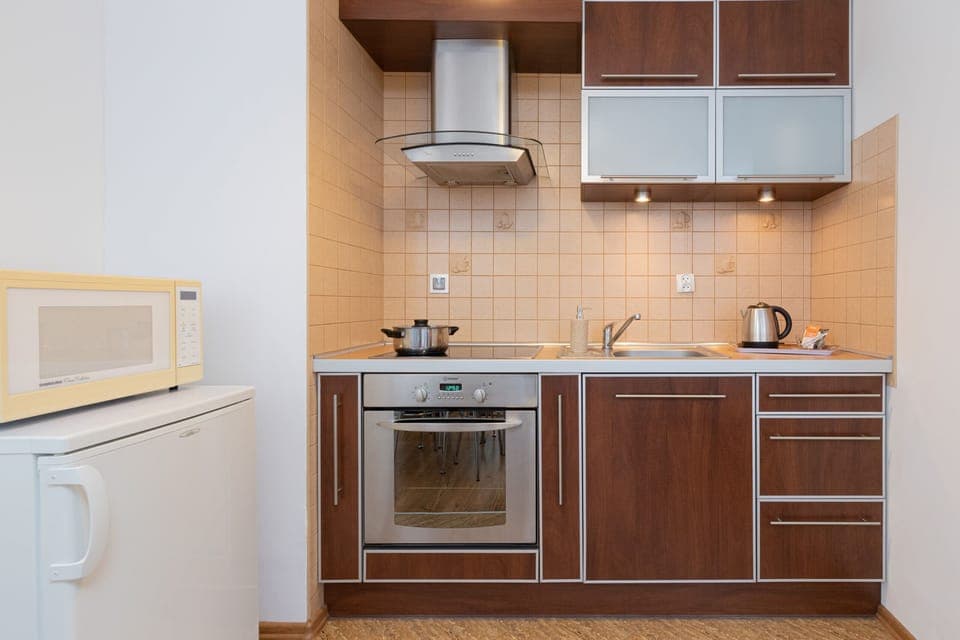 A compact kitchen equipped with wooden cabinets, a stovetop, and essential appliances.
