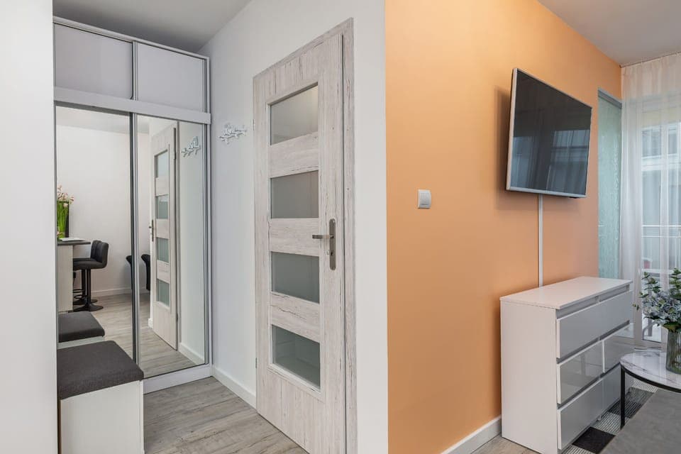 A modern hallway featuring frosted glass doors, neutral tones, and functional design elements.
