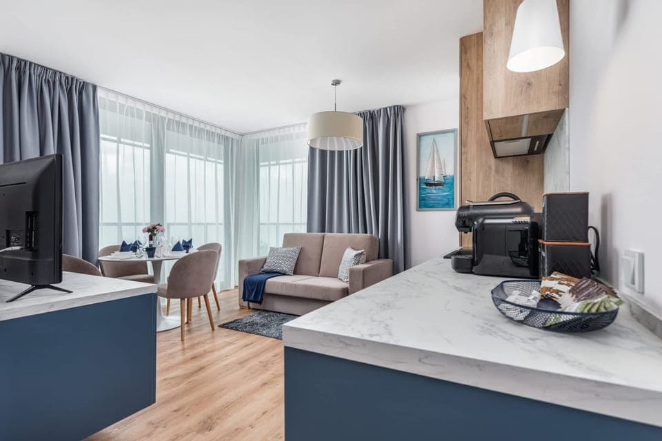 A combined view of the living room and kitchen area, featuring modern blue cabinetry and a comfortable seating area.