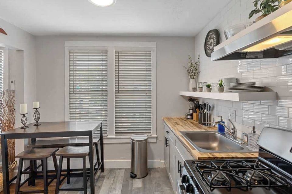 The kitchen has a gas stove and a dining table. 