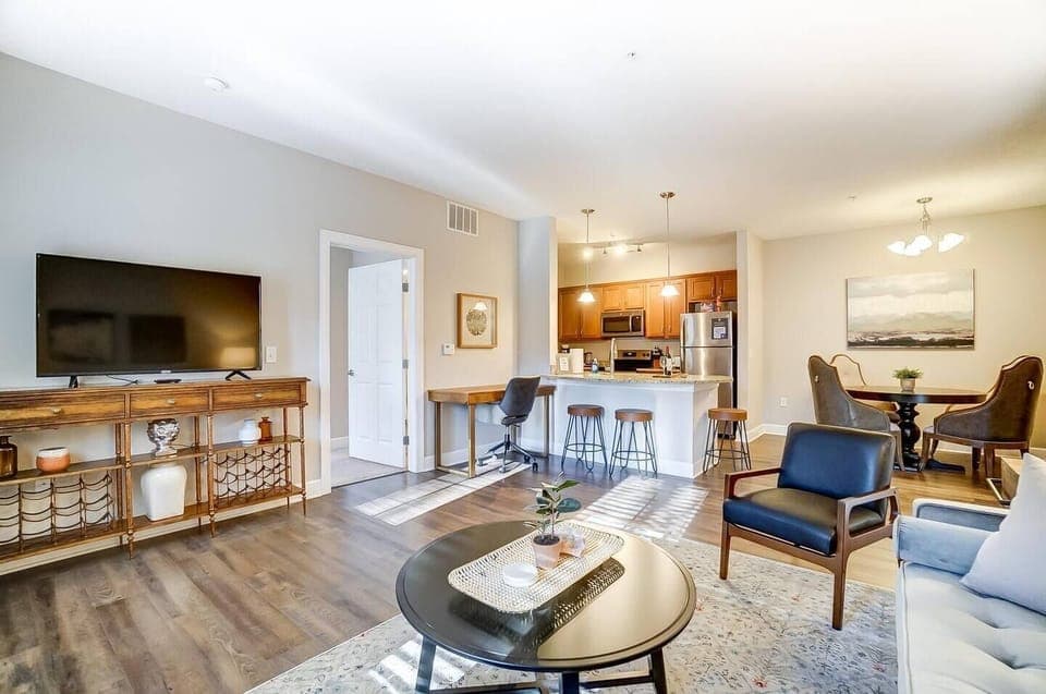 Spacious open-concept living area with office desk, bar stools, dining table, etc...tons of seating for an apartment! :) 