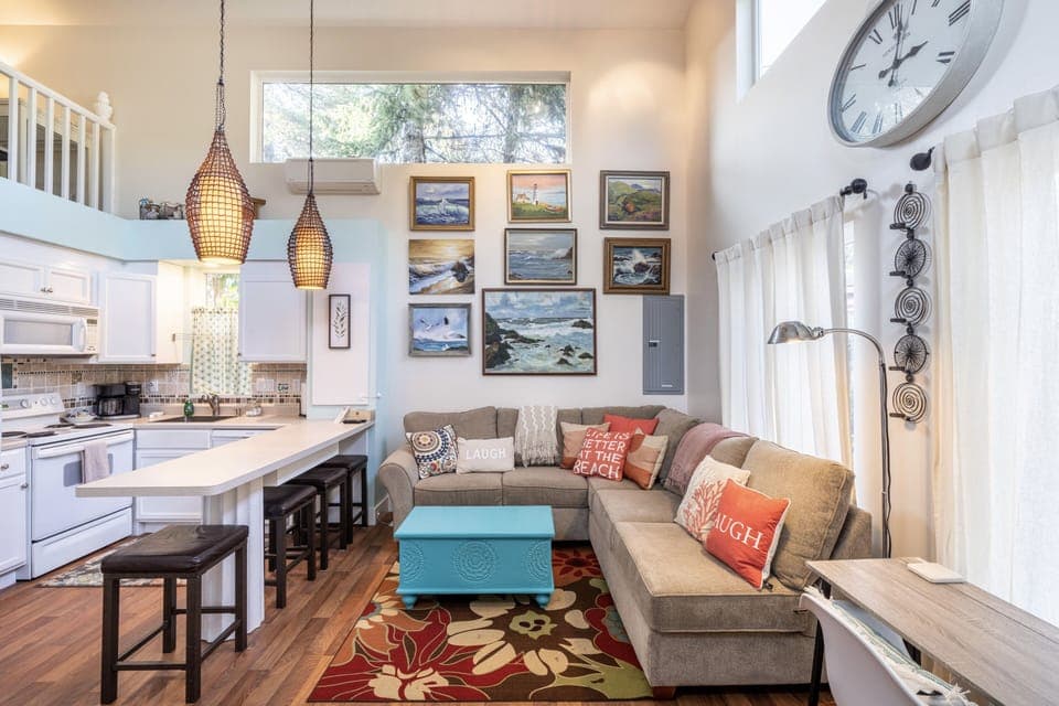Living area and gallery of sea-inspired art and desk with view of front yard.