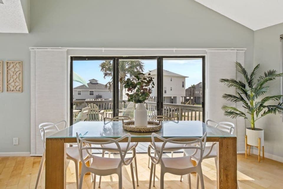 The light-wash wood of the dining table matches the coastal chic decor and palms in the home! The color scheme perfectly compliments the surrounding areas and enhances the home's appeal. It attracts positive vibes and is so relaxing!