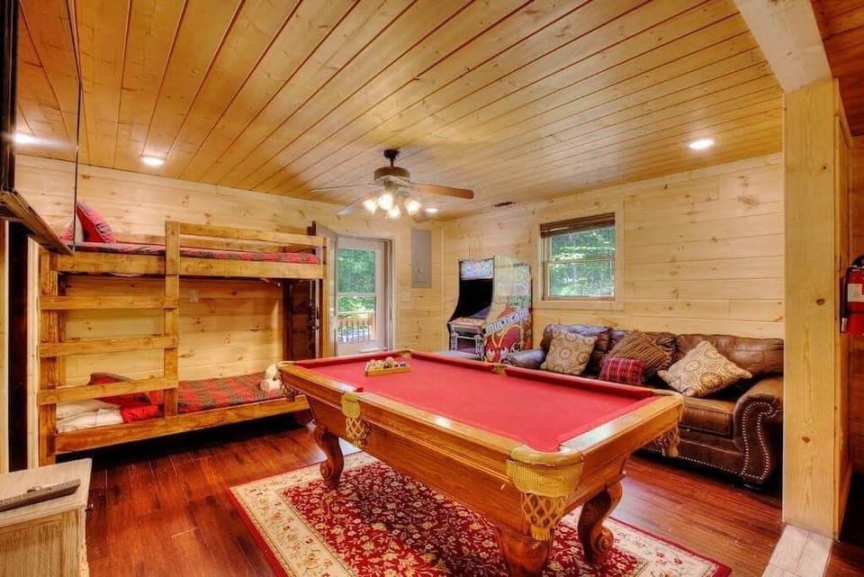 Enter in the side door that opens up to the game area of the downstairs living space. Game area includes an arcade  with hundreds of games, pool table, large flatscreen TV, and a twin bunk bed, with a full bathroom and laundry off this room. 