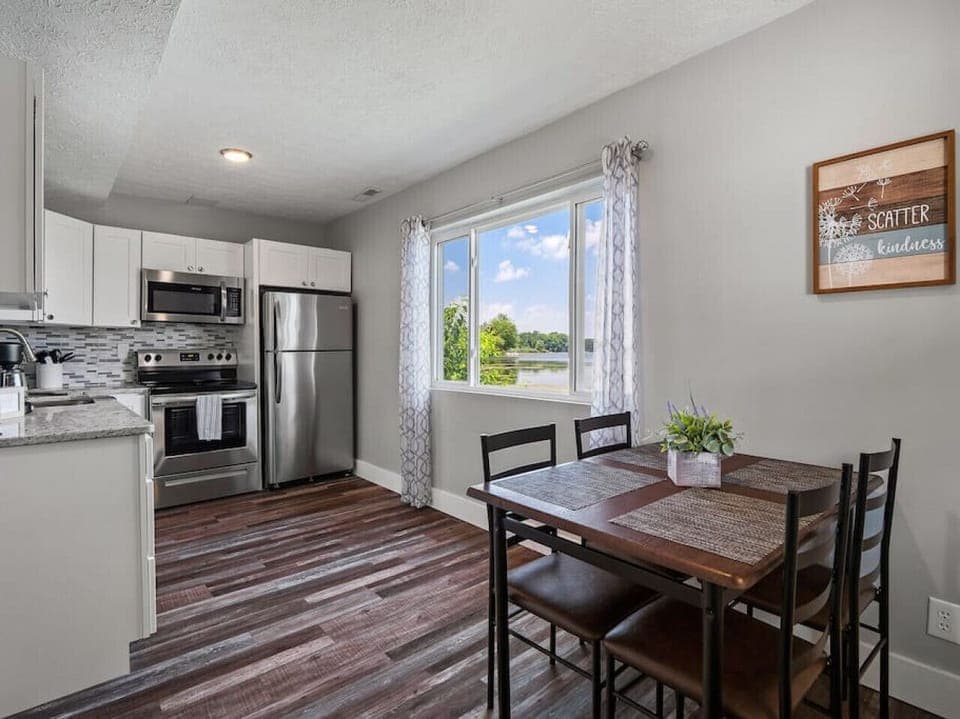 Kitchen and dining area with stainless appliances   - Window views overlooking sparkling lake scenery   - Perfect setup for shared meals and gatherings