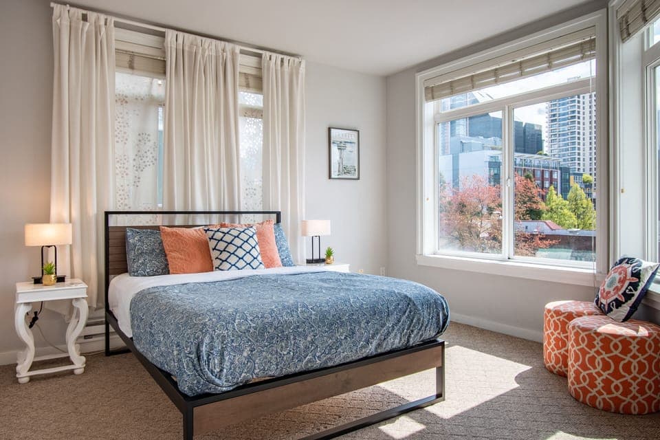 Comfortable queen bed in a spacious sun filled bedroom with water views.