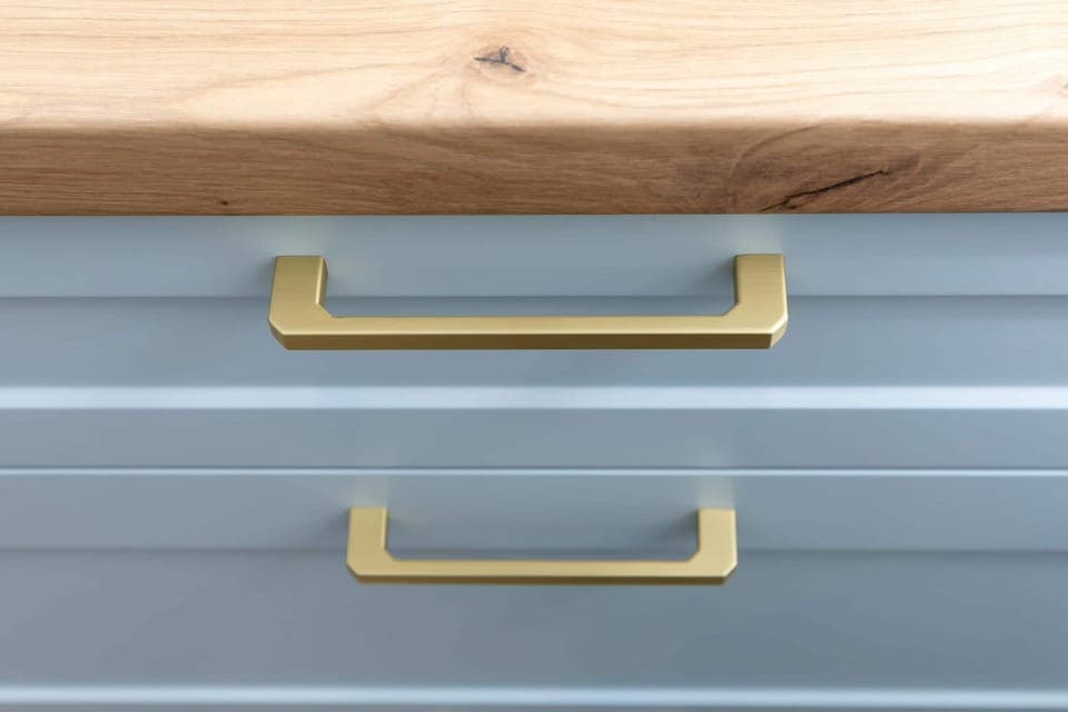 Close-up of a blue drawer with gold handles and wooden texture.
