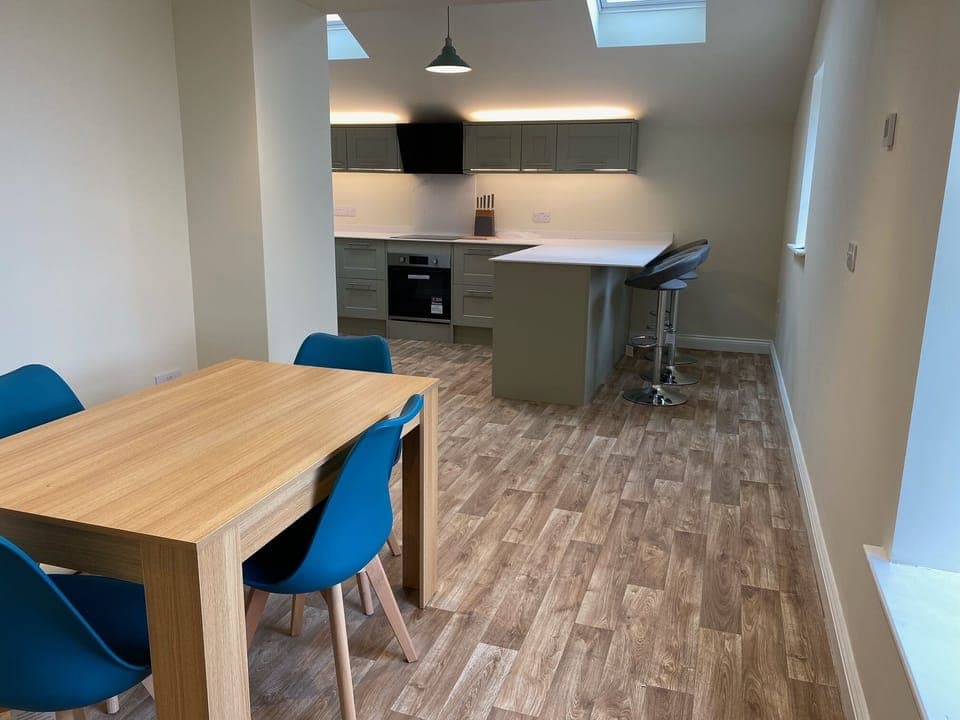An open plan dining space leading to the kitchen with breakfast bar