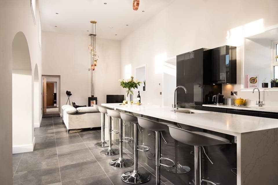 The Steading at West Lyham - spacious double-height kitchen with island and sitting room with corner sofa and MorsÃ¸ stove