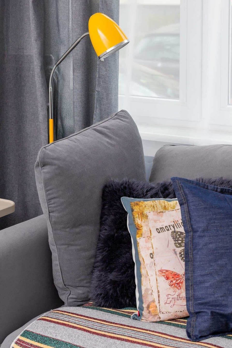 A close-up of curtains with decorative elements, including a colorful patterned cushion and cozy textiles.