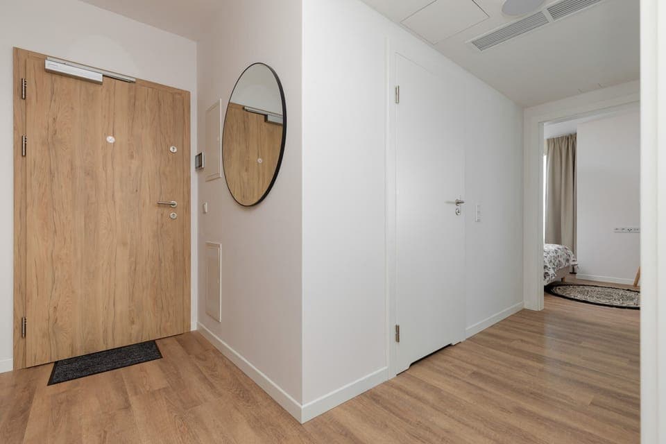 A bright and airy hallway with a circular mirror hanging on the wall.