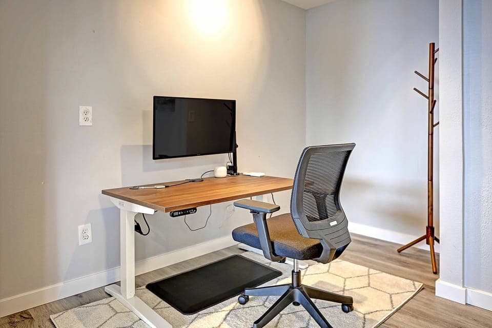 Work from home spot with a large monitor, adjustable standing desk and a chair.