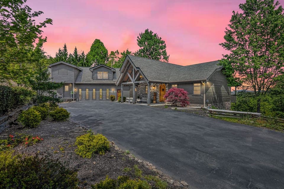 Luxury Smoky Mountains cabin exterior with long driveway, surrounded by trees and mountain scenery.