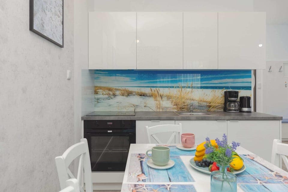 A sleek, modern kitchen with a dining table set for guests. The countertops are clean, with vibrant decor adding a pop of color.