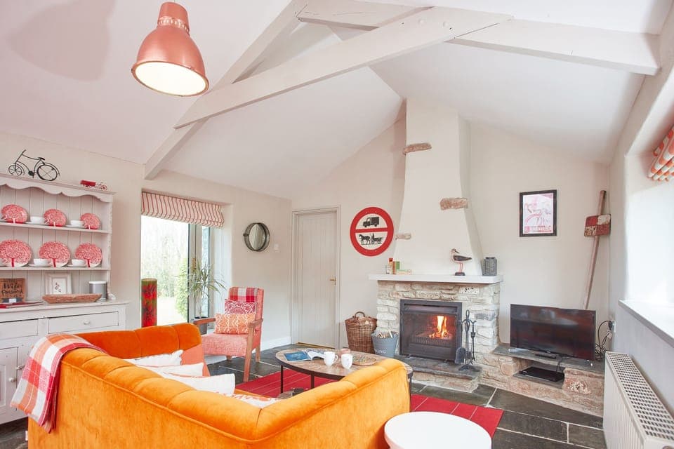 Meadow View, Newquay. Sitting room area with a plush velvet sofa, Smart television, wood burning stove and patio doors