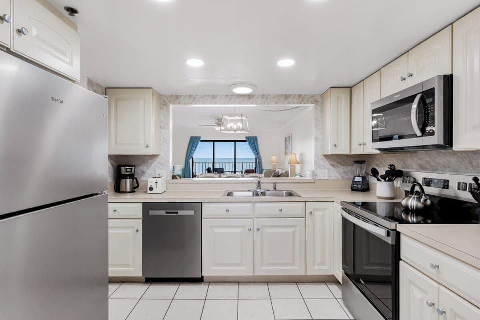 Your fully equipped kitchen features modern appliances and bright white cabinetry, with scenic ocean views beckoning through the living area.