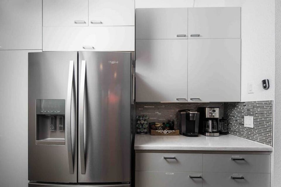 Start your day right in this modern kitchen nook, complete with a stainless steel fridge, Keurig and drip coffee makers, and a variety of pods and essentials—everything you need for a perfect morning brew!