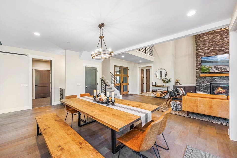 Modern lodge dining with seating for ten, soaring ceilings, and a cozy stone gas fireplace.