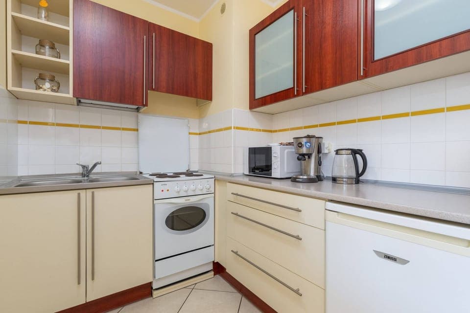 Fully equipped kitchen with white cabinetry, a stove, and wooden accents.
