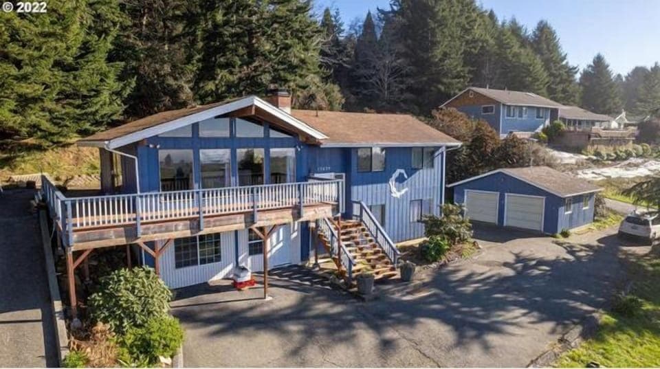 Coastal home framed by trees, steps from shimmering blue water.