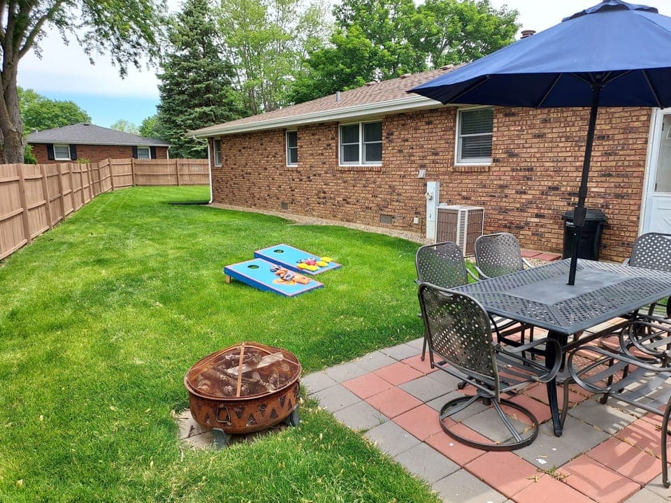 Fenced in back yard with fire pit, patio table with 6 chairs & corn hole game