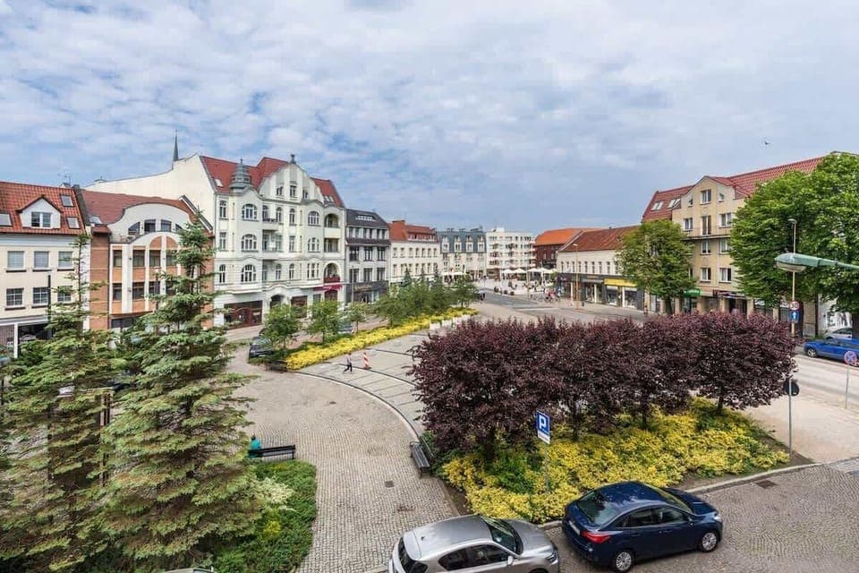A picturesque view of a historic town square with charming buildings, lush greenery, and a well-maintained urban landscape, adding to the scenic appeal.







