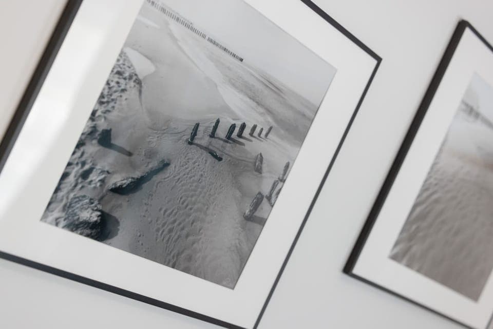 A close-up of three black-and-white framed photographs leaning against a wall. The artwork adds a modern, artistic touch.
