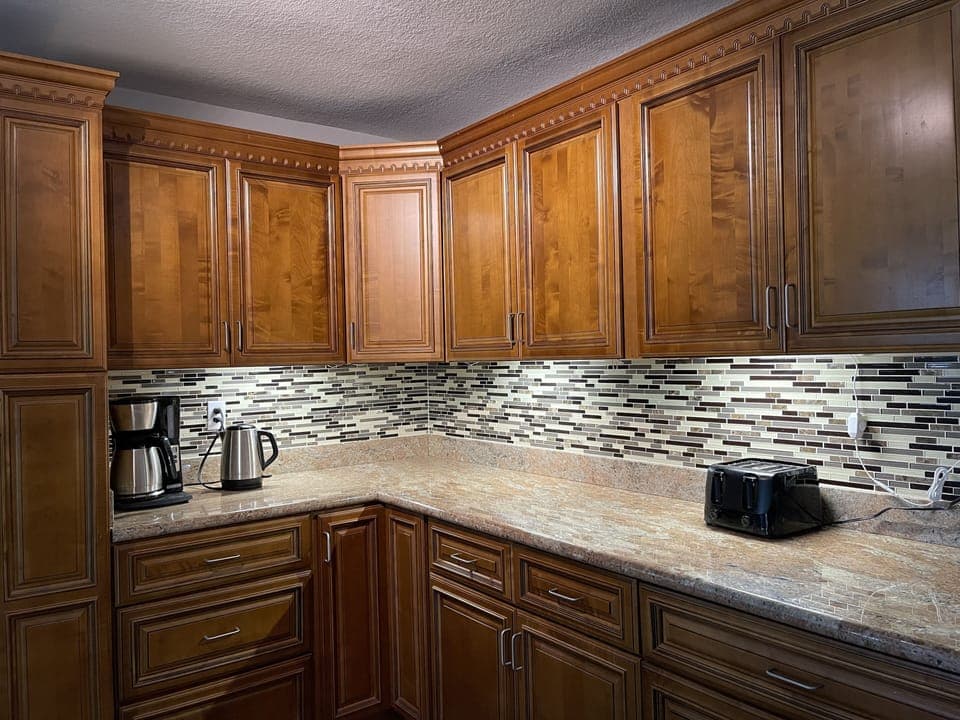 Coffee maker, water kettle, toaster. Kitchen has under cabinet lighting