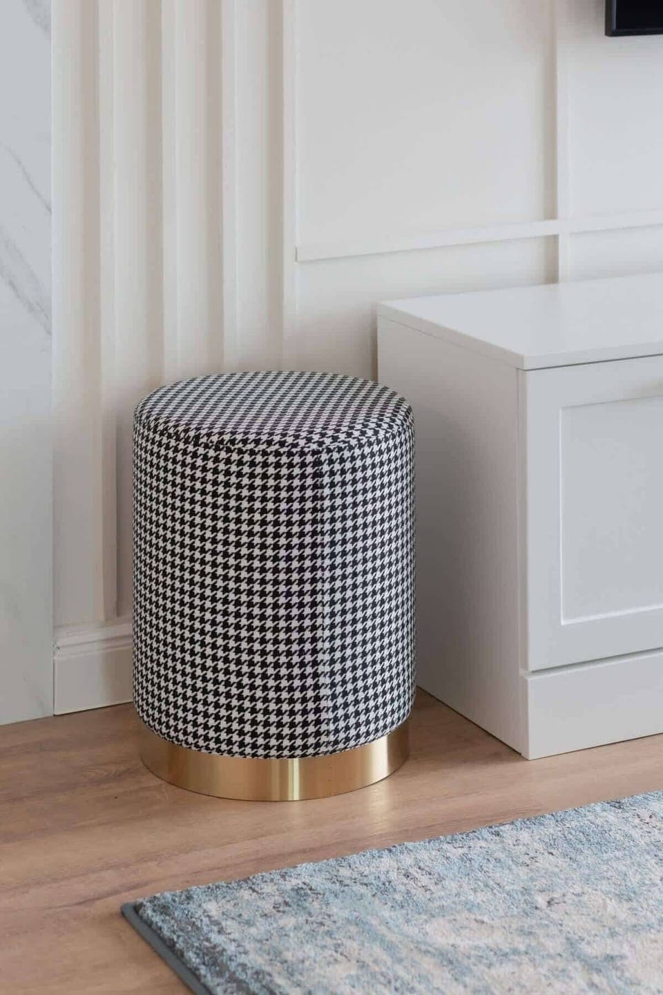 A small, stylish pouf in a neutral tone, adding functionality and comfort to the living space.
