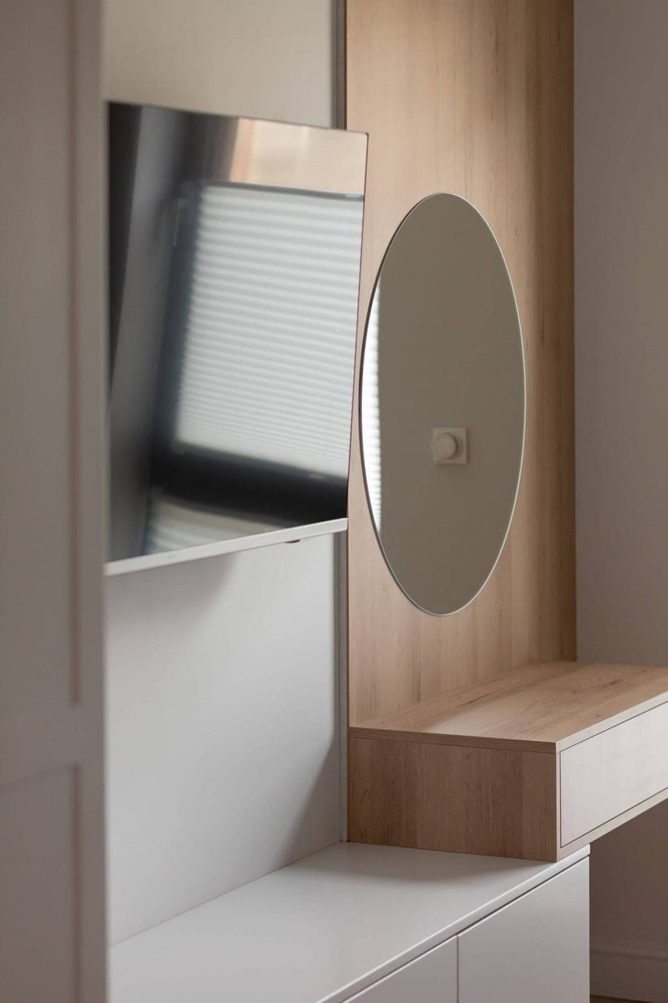 In the bedroom with a sofa there is a dressing table with a large round mirror.