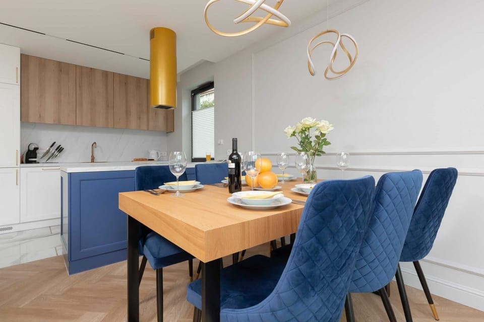 Harmoniously combined dining area with kitchenette the dining area consists of a wooden table and navy blue chairs that match the color of the kitchen furniture.