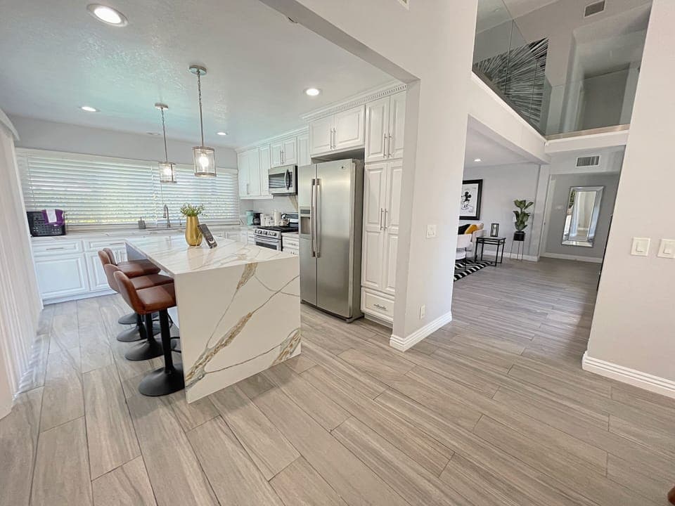 Modern marble rose quartz kitchen island with four barstools.