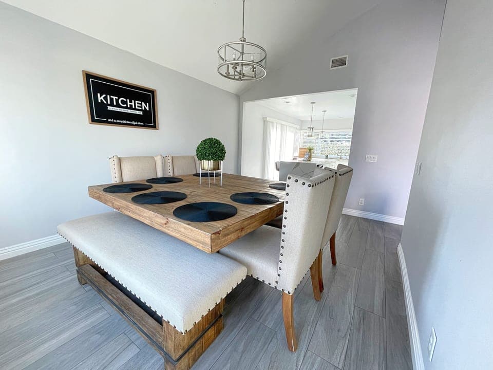 Modern solid wood dining table with four upholstered chairs and long bench.