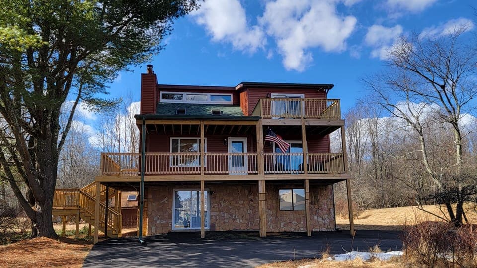 Front deck with seating and balcony with view of lake and pool