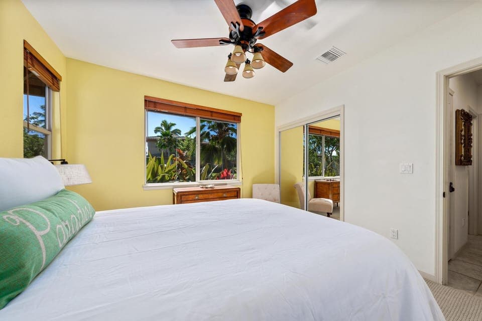 Cheerful queen bedroom with garden views through wide windows.