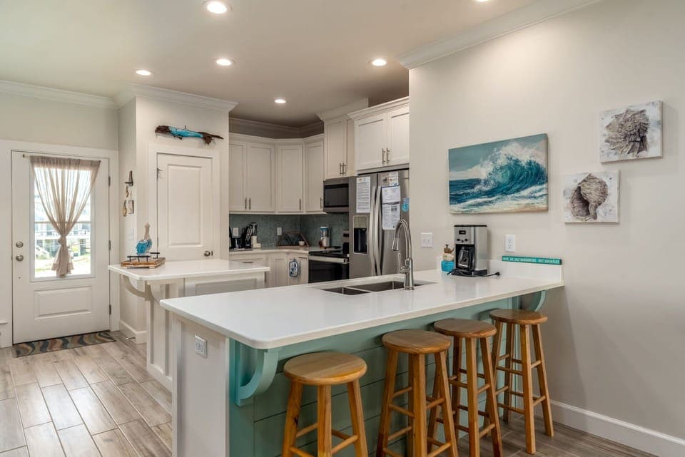 Your spacious kitchen invites culinary adventures with modern appliances, coastal artwork, and a perfect breakfast bar for morning coffee.