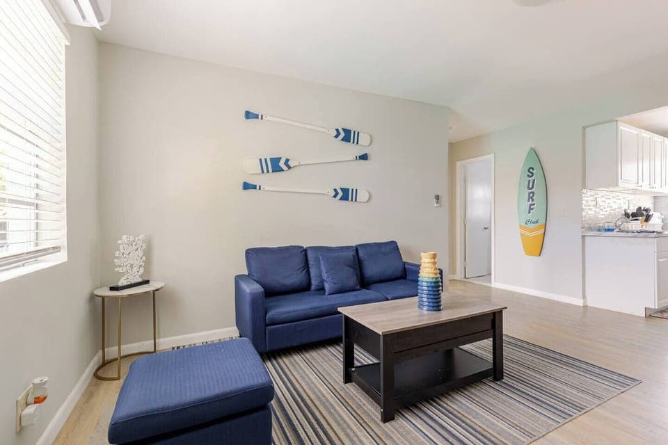 Cozy living room with a blue couch and decorative surfboards on the wall.