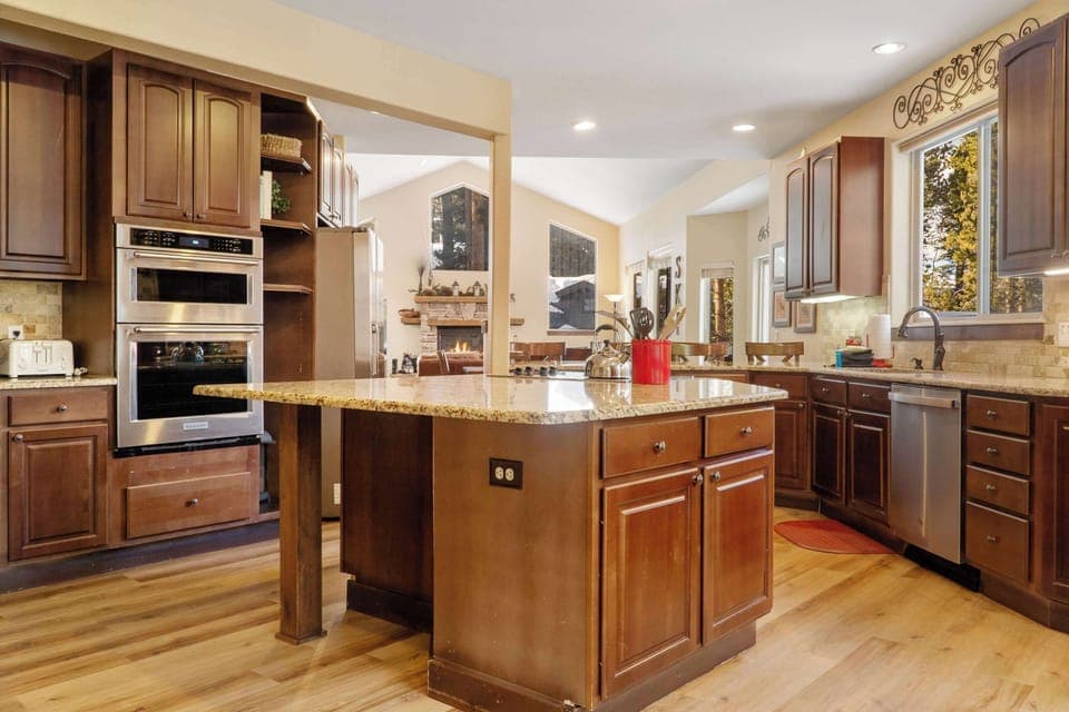 The fully equipped kitchen is a beautiful space with granite countertops, stainless steel appliances, and an over-the-sink window with tree views.