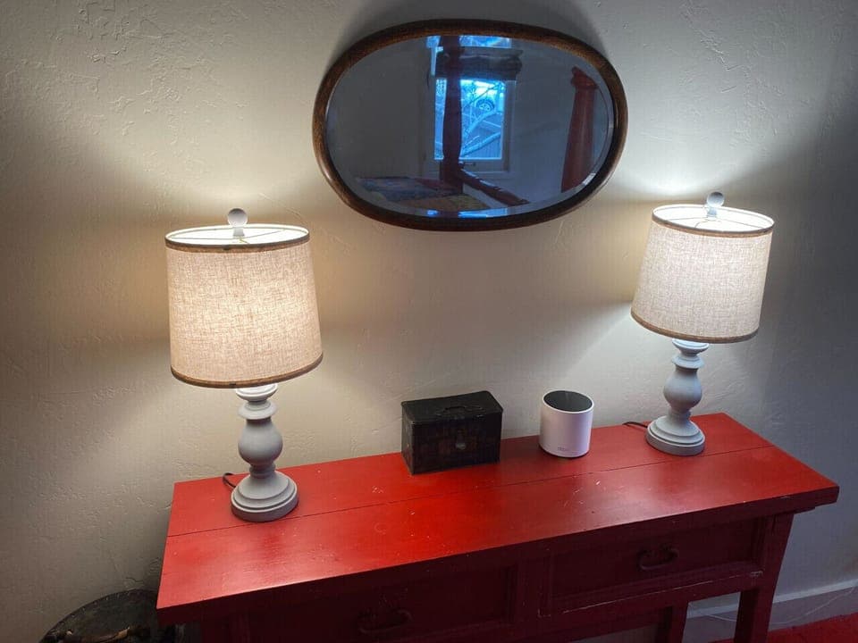 Cozy corner with vintage charm — featuring a bold red console table, soft ambient lighting, and a rustic mirror for a warm, inviting touch.