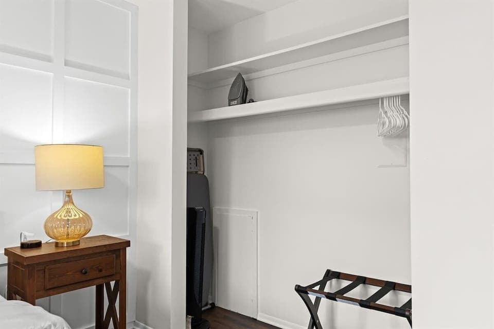 Spacious closet area equipped with hangers, ironing essentials, and a luggage rack—perfect for short or long stays