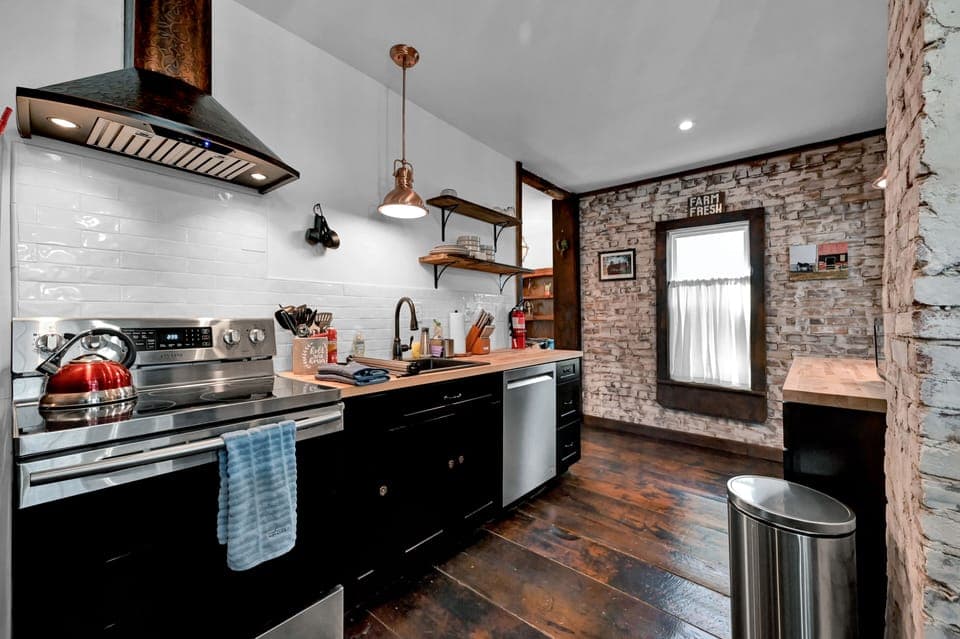 Modern kitchen with original brick walls and hardwood floors. 