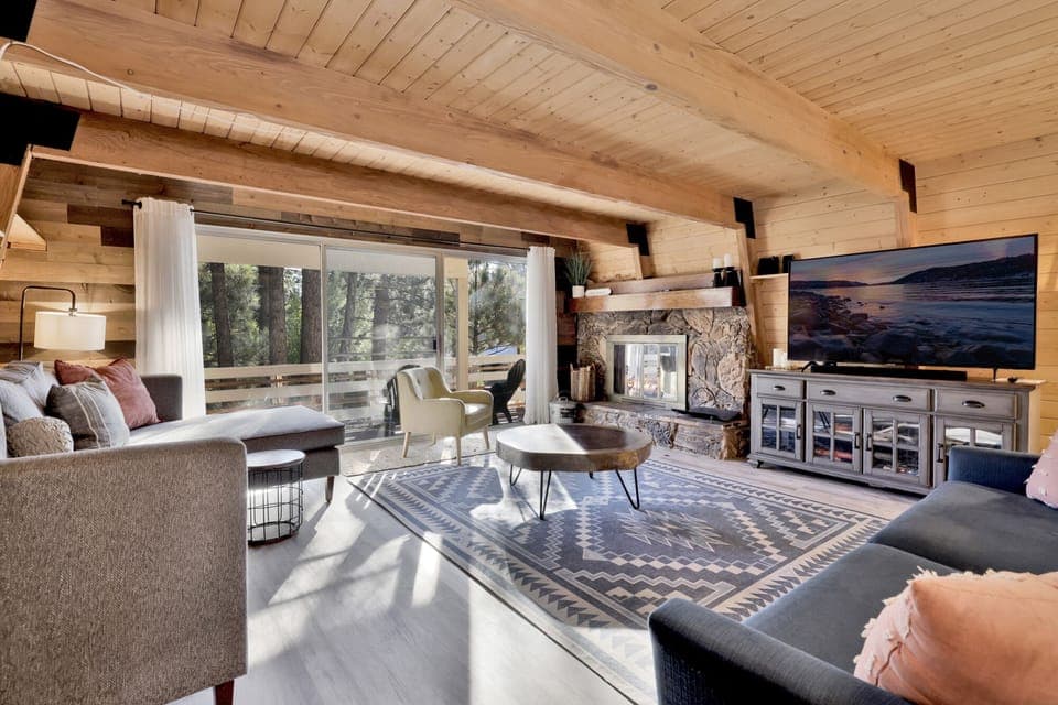 Cozy mountain living room with a stone fireplace, comfy seating, and smart TV perfect for relaxing evenings, movie nights, and warm cabin vibes after outdoor adventures.
