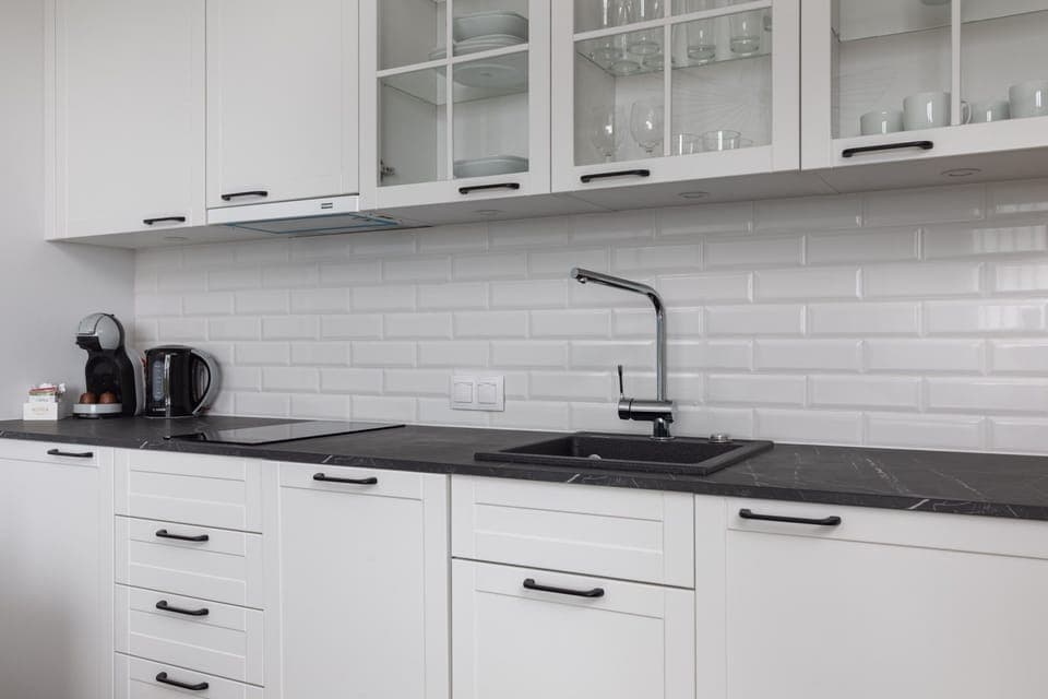 A compact kitchen with white cabinetry, a black countertop, and modern appliances, offering everything you need for cooking.