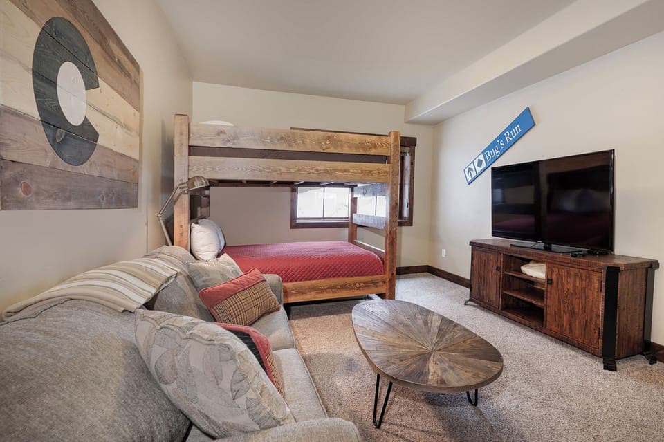 Your cozy bunkroom offers rustic charm with a comfortable sectional, flat-screen TV, and thoughtful touches perfect for relaxing after mountain adventures.