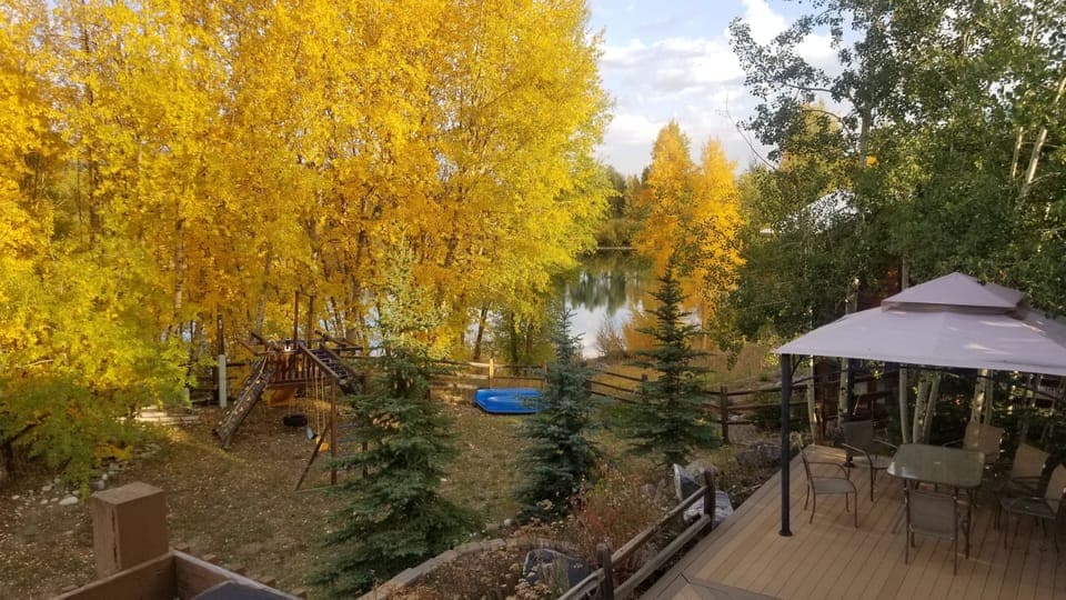 Beautiful backyard area features a playset, pond, and large private deck area.