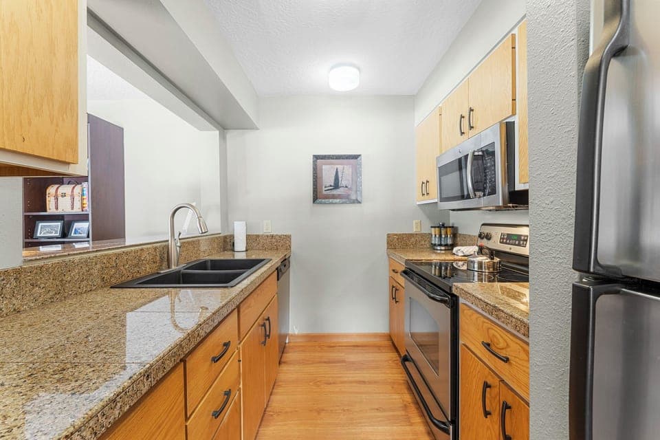 Full kitchen with granite countertops and stainless steel appliances.