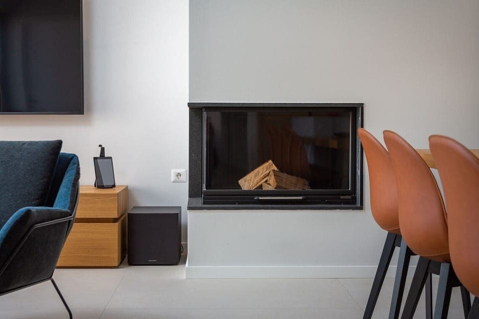 A wood-burning fireplace next to the TV in the living room and chairs around the kitchen island on the ground floor of the luxury villa Murter Exotic